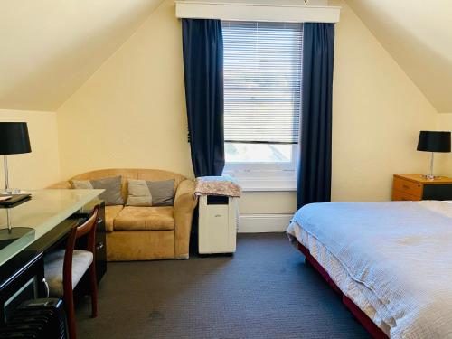 a bedroom with a bed and a desk and a window at The Mews Motel in Launceston