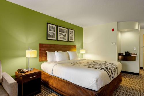 a hotel room with a large bed and a chair at Sleep Inn & Suites Harbour Pointe in Brandermill