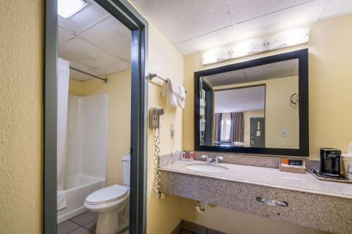 een badkamer met een wastafel, een toilet en een spiegel bij Econo Lodge Kearney - Liberty in Kearney