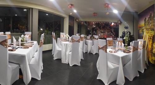a row of tables in a room with white table settings at TL Casa Blanca Hotel Boutique Sibundoy Putumayo in Sibundoy