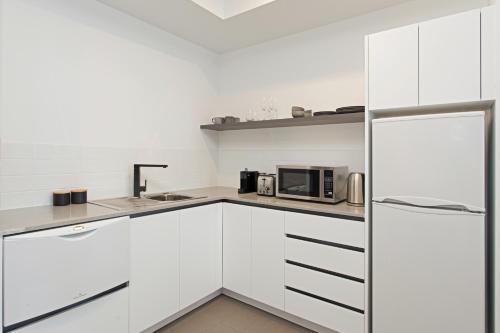 a white kitchen with a sink and a microwave at Mantra Traralgon in Traralgon