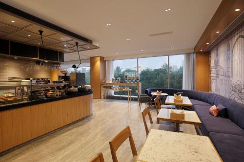 a restaurant with a couch and tables and a kitchen at Holiday Inn Express Hyderabad Banjara Hills by IHG in Hyderabad