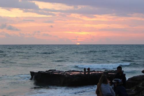 a group of people standing on a rock in the ocean at The Calmtree Bungalows in Canggu