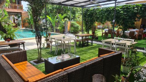 a patio with tables and chairs and a pool at Dewi Sri Guesthouse in Mataram