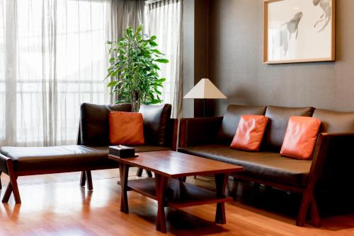 a living room with a couch and a coffee table at Oriens Hotel & Residences Myeongdong in Seoul