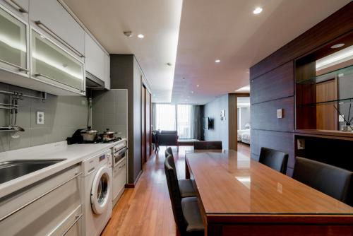 a kitchen with a wooden table and a dining room at Oriens Hotel & Residences Myeongdong in Seoul