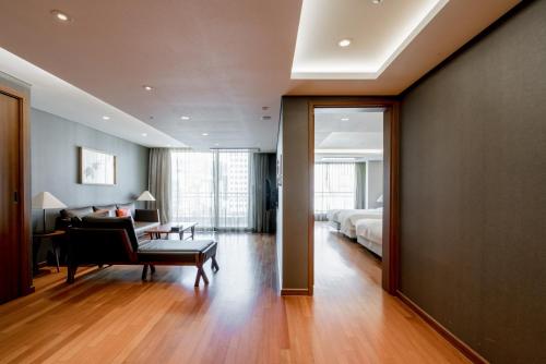 a bedroom with a bed and a living room with a couch at Oriens Hotel & Residences Myeongdong in Seoul