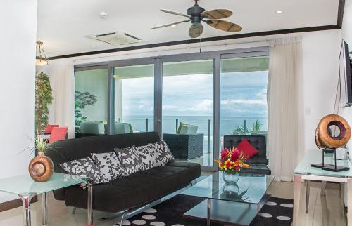 a living room with a black couch and a large window at Best in Jaco Condos at Diamante del Sol in Jacó