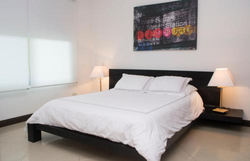 a bedroom with a large white bed with two lamps at Best in Jaco Condos at Diamante del Sol in Jacó