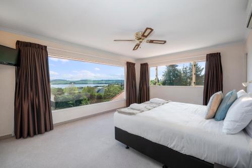 a bedroom with a bed and a large window at Tui Lookout - Spa Pool & Lake Views in Taupo