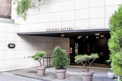 a building with three potted trees in front of it at Oriens Hotel & Residences Myeongdong in Seoul