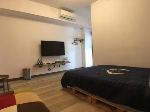 a bedroom with a bed and a flat screen tv at TainanHyggeAnping in Tainan