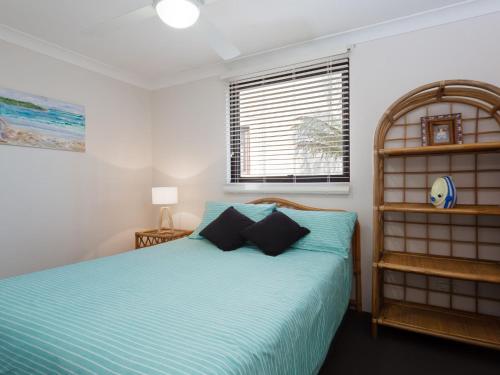 a bedroom with a bed with blue sheets and a window at Carindale, 13 19 Dowling Street - Ground floor unit with complex pool and tennis court in Nelson Bay