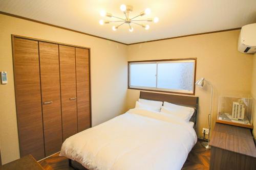 a bedroom with a large white bed with a window at Private house En Sagisu #OF1 in Osaka