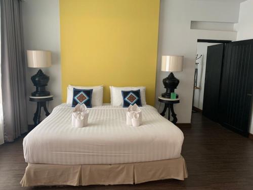 a bedroom with a large white bed with two packages on it at Fullrich Lanna Suite in Chiang Mai