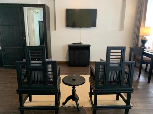 a living room with two chairs and a table and a tv at Fullrich Lanna Suite in Chiang Mai