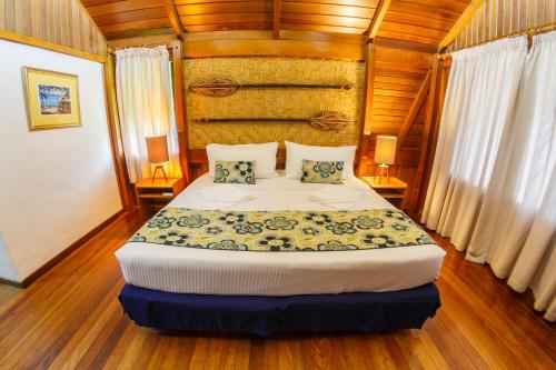 1 dormitorio con 1 cama en una habitación con paredes de madera en Kokopo Beach Bungalow Resort, en Kokopo