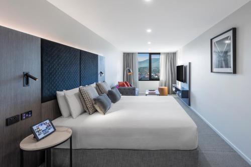 a bedroom with a large white bed and a couch at Deco Hotel Canberra in Canberra