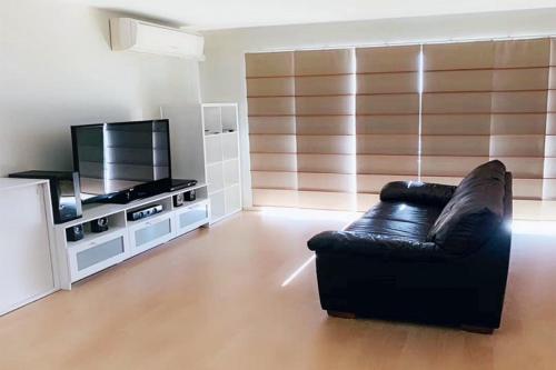 a living room with a black leather couch and a television at Forest Lake best stay in Wacol