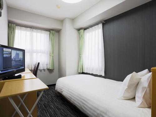 a hotel room with a bed and a desk with a computer at Business Hotel Sunpalace in Tokyo
