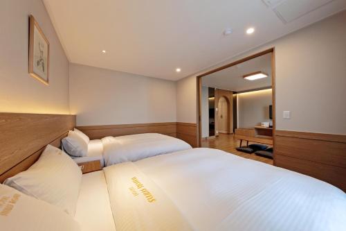 a hotel room with two beds and a mirror at Benikea Swiss Rosen Hotel in Gyeongju