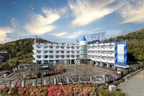 a large white hotel with a mountain in the background at Benikea Swiss Rosen Hotel in Gyeongju
