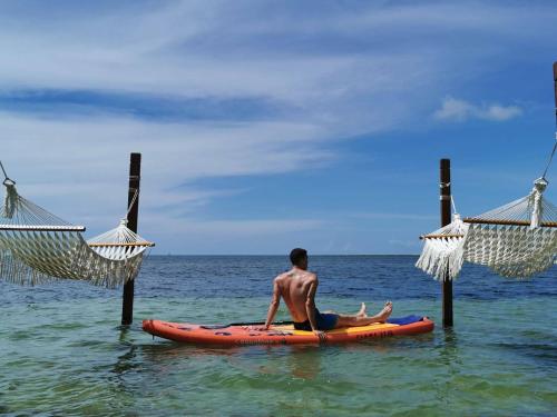 a man sitting on a surfboard in the water at Rocky's Boutique Resort - Veranda Collection Samui - SHA Extra Plus in Lamai