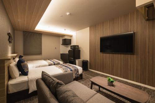 a hotel room with two beds and a flat screen tv at GRAND BASE Kagoshima Tenmonkan in Kagoshima