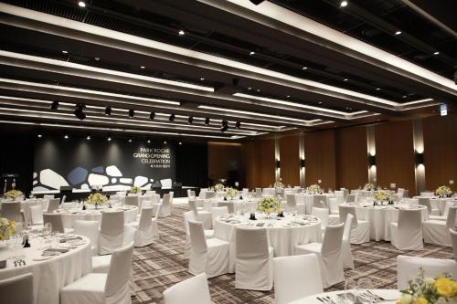 un salón de banquetes con mesas blancas y sillas blancas en PARK ROCHE Resort & Wellness, en Jeongseon