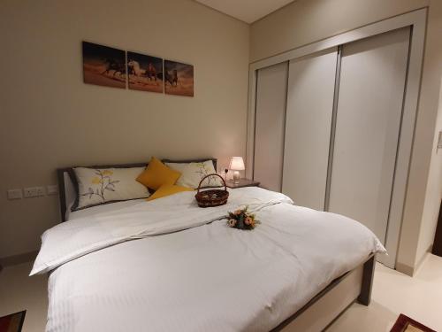 ein Schlafzimmer mit einem Bett mit weißer Bettwäsche und einem Korb darauf in der Unterkunft Lovely Apartment in Jebel Sifah with private Garden - As sifah in Muscat