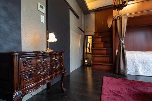 a bedroom with a bed and a dresser with a lamp at Creare Ryogoku in Tokyo