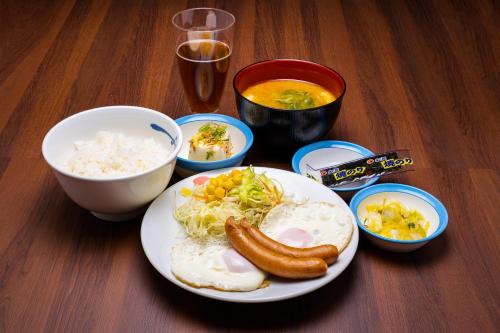 a table with a plate of food and bowls of food at KOKO HOTEL Hiroshima Ekimae in Hiroshima