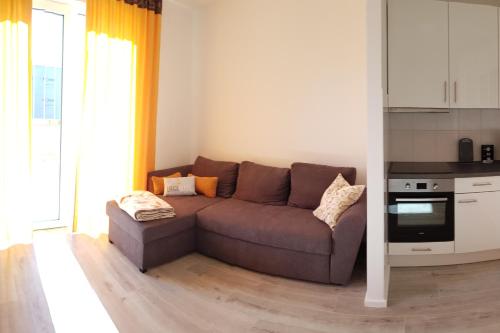 sala de estar con sofá marrón en la cocina en Ferienwohnung in Birkenwerder mit Balkon, en Birkenwerder
