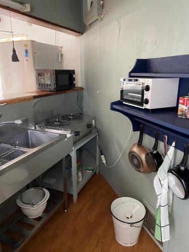 eine kleine Küche mit einer Spüle und einer Mikrowelle in der Unterkunft Kamakurayama Holiday Flat in Kamakura