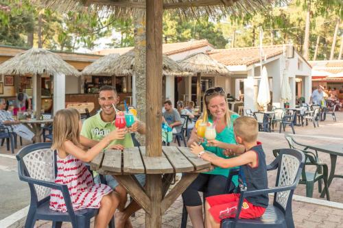 um grupo de pessoas sentadas à mesa com bebidas em Mobil Home 4 chambres - Camping Palmyre Loisirs em Les Mathes