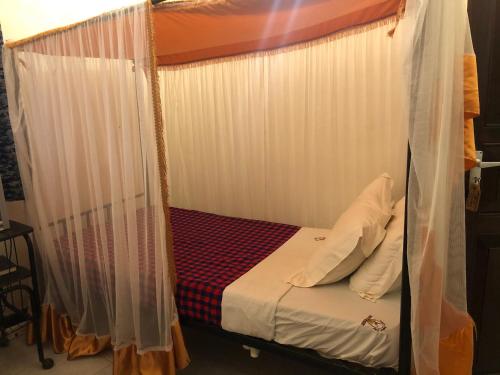 1 cama con dosel y cortinas blancas en una habitación en Impala Safari Lodge en Voi