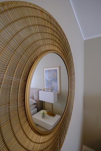 a round rattan mirror in a room with a bed at Sjøgata Gjestehus in Larvik