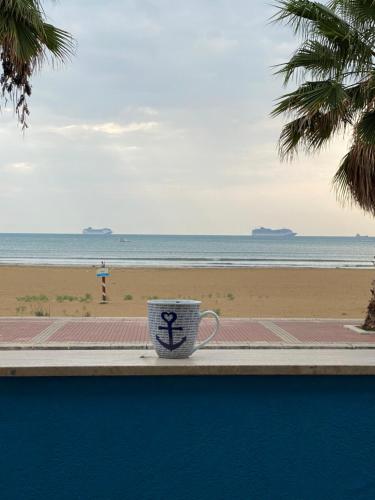 a coffee cup sitting on a ledge next to the beach at Terrazze Sul Mare in Pozzallo