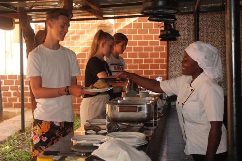 a group of people standing in a kitchen preparing food at Impala Safari Lodge in Voi