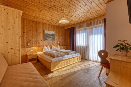 a bedroom with a bed in a room with wooden walls at Garni Appartments Helvetia in Villabassa