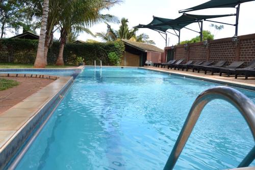 a large swimming pool with blue water and chairs at Impala Safari Lodge in Voi