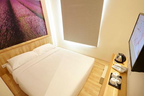 um pequeno quarto com uma cama e uma televisão em Hotel Six Seasons @ Mid Valley em Kuala Lumpur