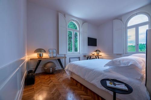 a white bedroom with a bed and two windows at Villa Monty Banks in Cesena