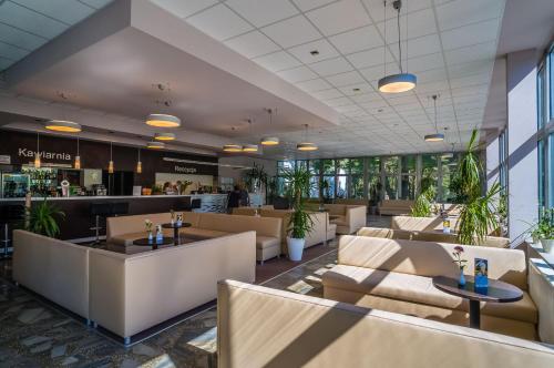 un restaurante con sofás, mesas y plantas en Hotel *** NAT Krynica Morska en Krynica Morska