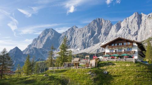 een hotel op een heuvel met bergen op de achtergrond bij Berghotel Türlwand in Ramsau am Dachstein