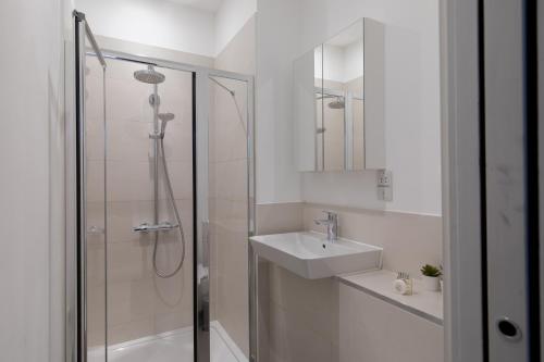 a white bathroom with a shower and a sink at London City Apartments - Luxury and spacious apartment with balcony in London