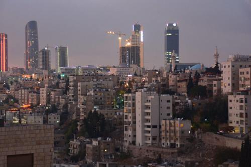 vista para uma cidade à noite com edifícios altos em The Y Hotel em Amã