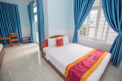 a bedroom with a bed with blue curtains and a window at Hotel Dang Khoa in Con Dao