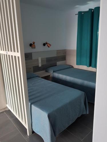 two beds in a room with blue sheets at Atlantis Las Lomas in Puerto del Carmen
