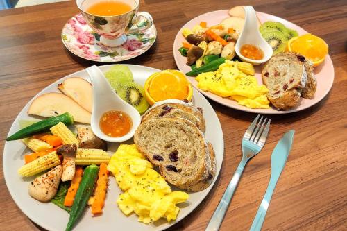 stół z 3 talerzami produktów śniadaniowych i filiżanką herbaty w obiekcie 魚兒尖尖民宿 w mieście Yuchi